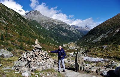 Portrait of senior man standing on mountain against sky