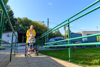 Mother pushing a wheelchair with her daughter, girl living with cerebral palsy.