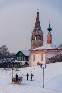 People on snow field against historic church