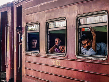 Portrait of people sitting on train window