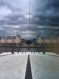 View of buildings in front of river against cloudy sky