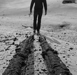 Low section of man walking on beach