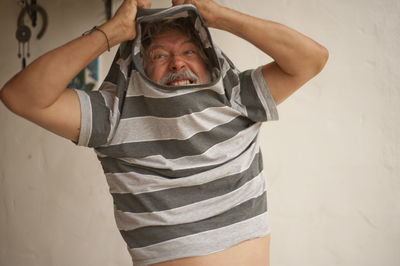 Portrait of man standing against wall at home