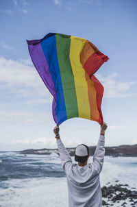 Male tourist holding lgbtqi flag at el golfo during vacations, lanzarote, spain