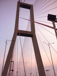 Low angle view of suspension bridge against sky in evening 