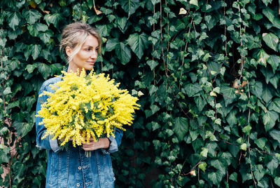 Woman standing by yellow flowering plants