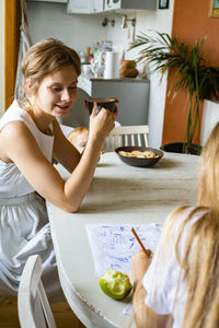 Portrait of smiling young woman sitting on table at home