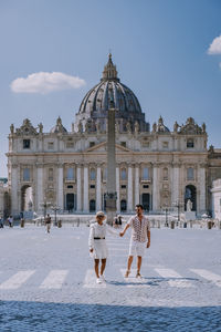 Couple outside historic building against sky in city