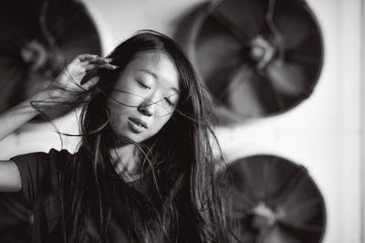 Young woman with tousled hair standing against exhaust fans