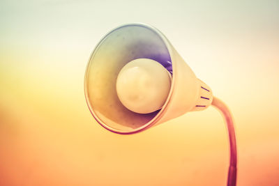 Close-up of electric lamp against orange background