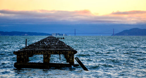 Bridge over sea against sky during sunset