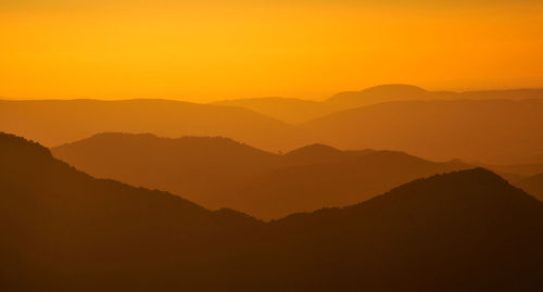 Scenic view of silhouette mountains against orange sky