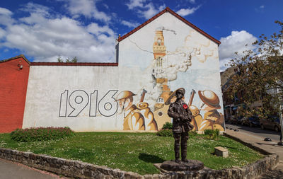 Graffiti on statue by building against sky