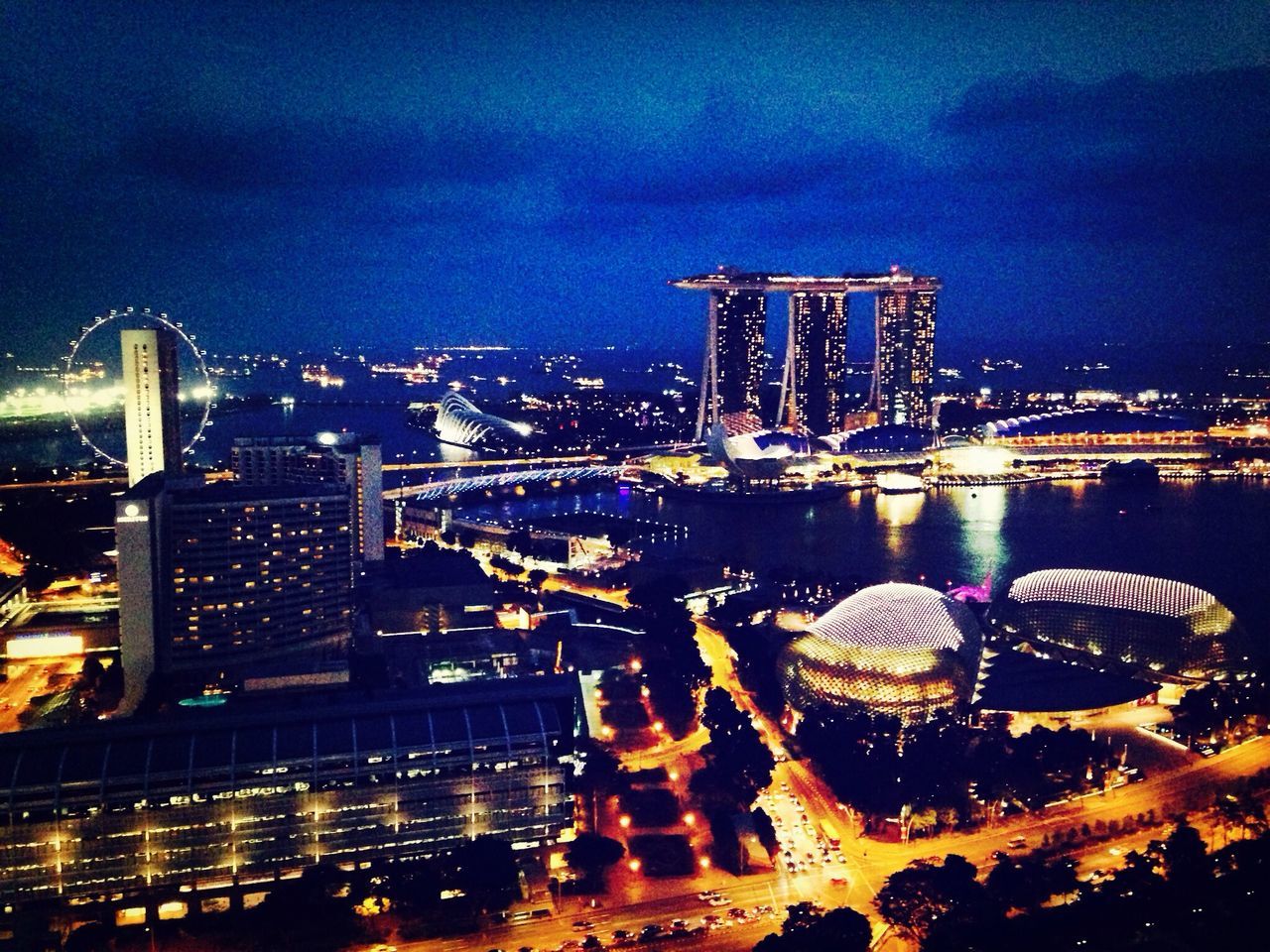 illuminated, night, city, architecture, building exterior, built structure, cityscape, sky, skyscraper, tall - high, modern, city life, travel destinations, capital cities, tower, urban skyline, office building, light - natural phenomenon, river, cloud - sky