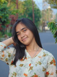 Portrait of smiling young woman standing against plants