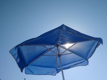 Low angle view of umbrella against clear blue sky