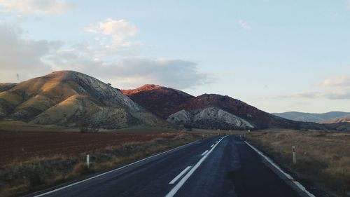 Country road along landscape and colourful mountains against sky