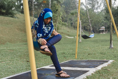 Girl sitting on swing at playground