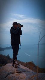 Man photographing sea against sky