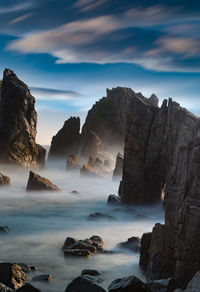 Scenic view of rocks in sea against sky