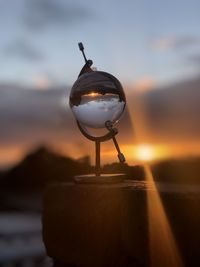 Close-up of crystal ball on table against sky during sunset