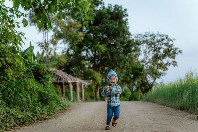 Portrait of happy boy walking on country road