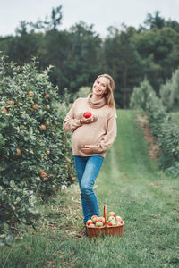 Full length of woman eating apple on field