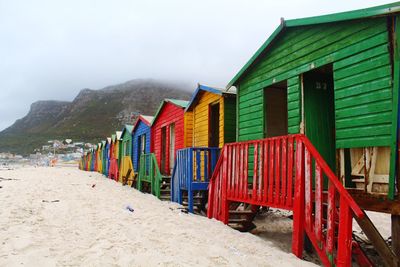 Beach huts by buildings against sky