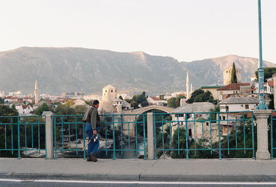 Man and buildings in city against clear sky