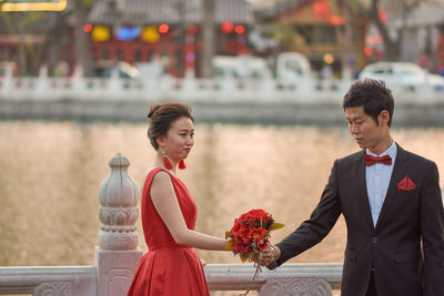 Couple holding red while standing against blurred background