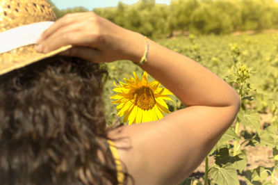 Rear view of woman with yellow flower by plants