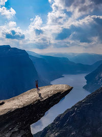 High angle view of man doing handstand on rock by mountains against sky