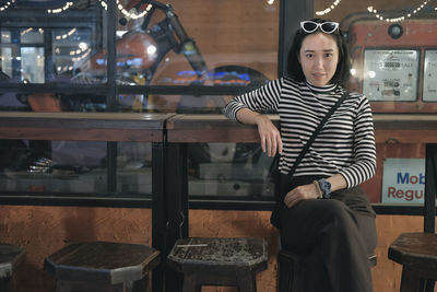 Portrait of young woman sitting on chair in cafe