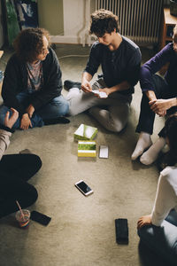 High angle view of teenagers playing board game in bedroom at home