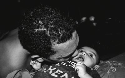 Father kissing toddler sitting on bed