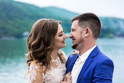 Smiling couple standing against lake