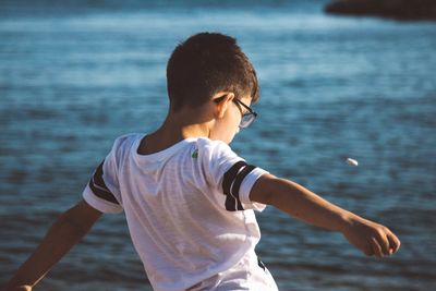 Boy standing at beach against sky