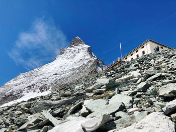 Low angle view of snowcapped mountain against blue sky