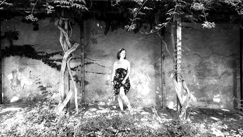 Full length of young woman standing on tree trunk