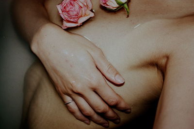 Midsection of shirtless woman covering breast in bathtub