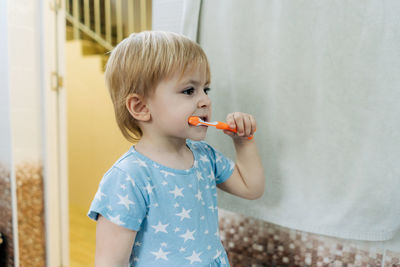 A little girl learns to brush her teeth on her own in the bathroom.