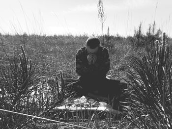 Woman sitting on field against sky