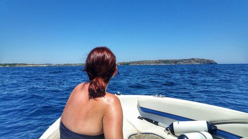 Woman traveling on boat sailing in sea against clear blue sky