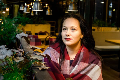 Young woman wrapped in blanket sitting at restaurant