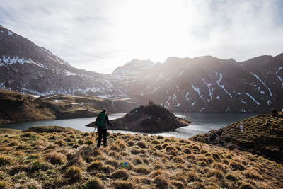 Rear view of man standing on mountain against sky