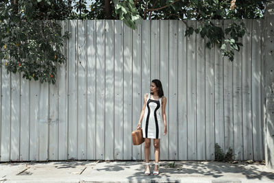 Full length of woman standing by wall outdoors