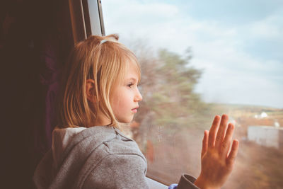 Side view of girl looking through window