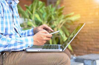 Midsection of man using mobile phone