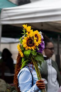 Low angle view of people holding bouquet of flowering plant