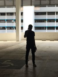 Silhouette man talking on mobile phone while standing against building